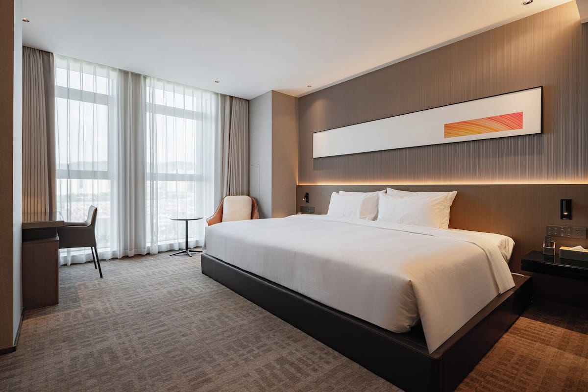 Ein modernes Hotelzimmer mit einem großen Bett, einem Schreibtisch und einem Stuhl.