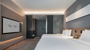 Una habitación de hotel moderna con una cama grande, un televisor montado en la pared y un baño independiente.