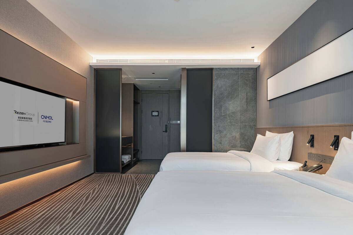 Ein modernes Hotelzimmer mit einem großen Bett, einem an der Wand befestigten Fernseher und einem separaten Badebereich.