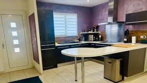 Une cuisine moderne dotée d’un îlot central, d’appareils électroménagers en acier inoxydable et d’un mur d’accent violet.