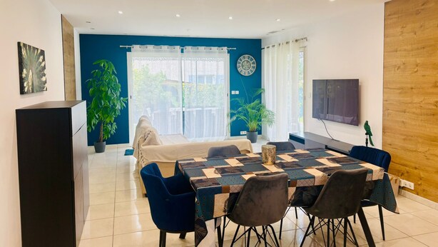 Un espace repas moderne avec une table à carreaux, des chaises bleues et une grande fenêtre avec des rideaux.