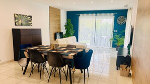 Un espace repas moderne avec une grande table et des chaises, un canapé et une plante en pot.
