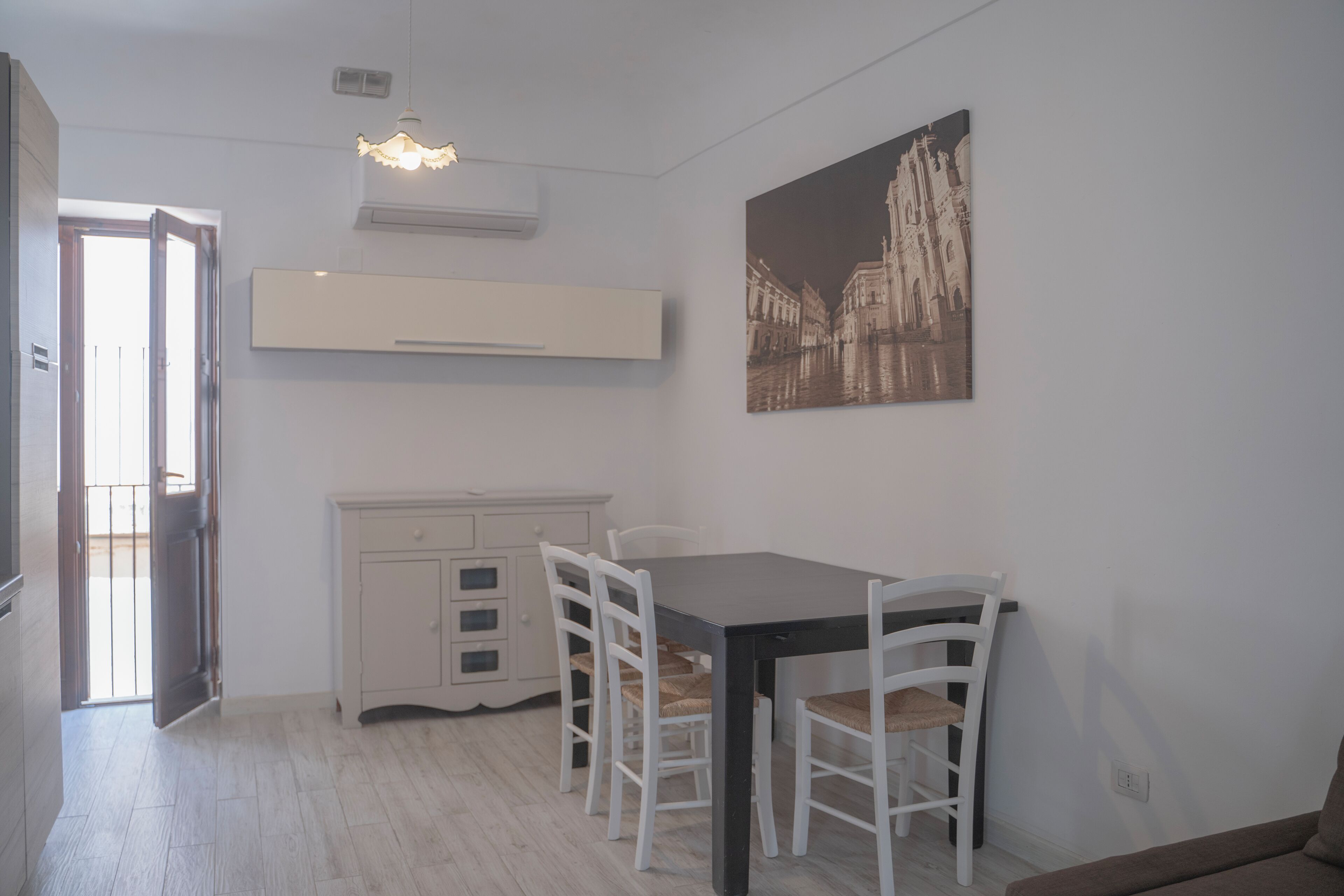 Un coin repas comprenant une table et des chaises, un meuble blanc et un climatiseur fixé au mur.