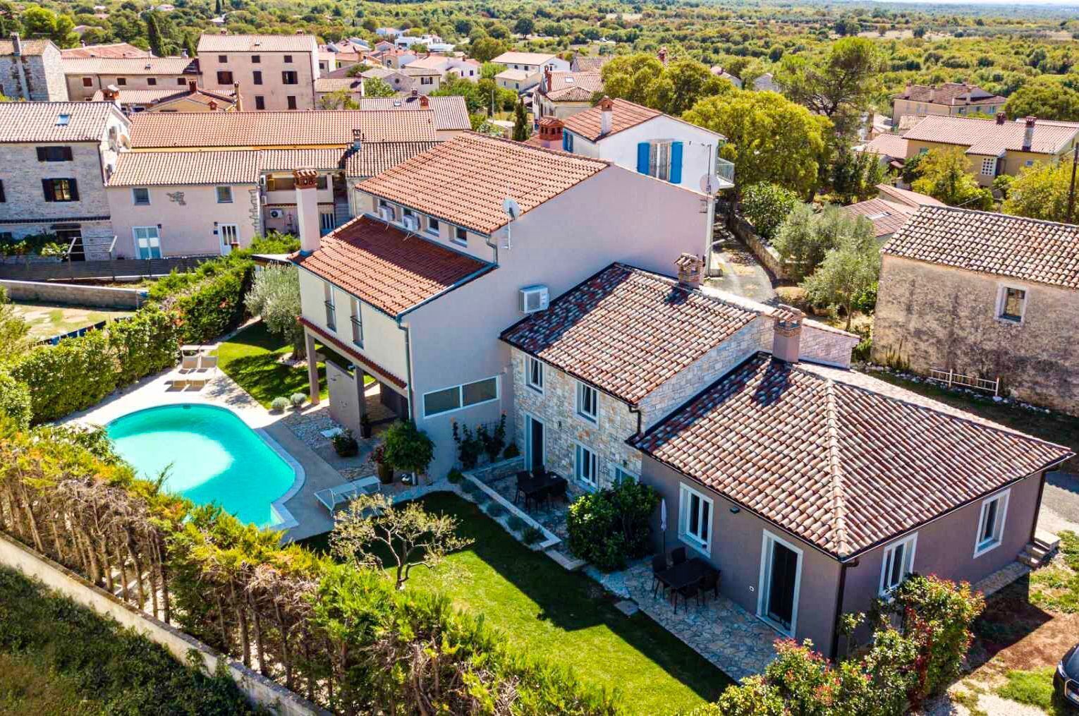 Eine moderne Villa mit Schwimmbad, umgeben von üppiger Vegetation und traditioneller Architektur.