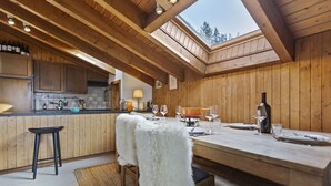 A cozy kitchen with wooden beams, a skylight, and a dining area with a table set for two. - Piscine, Ski & Vue sur le lac – Crans 6 pers (Crans-Montana)