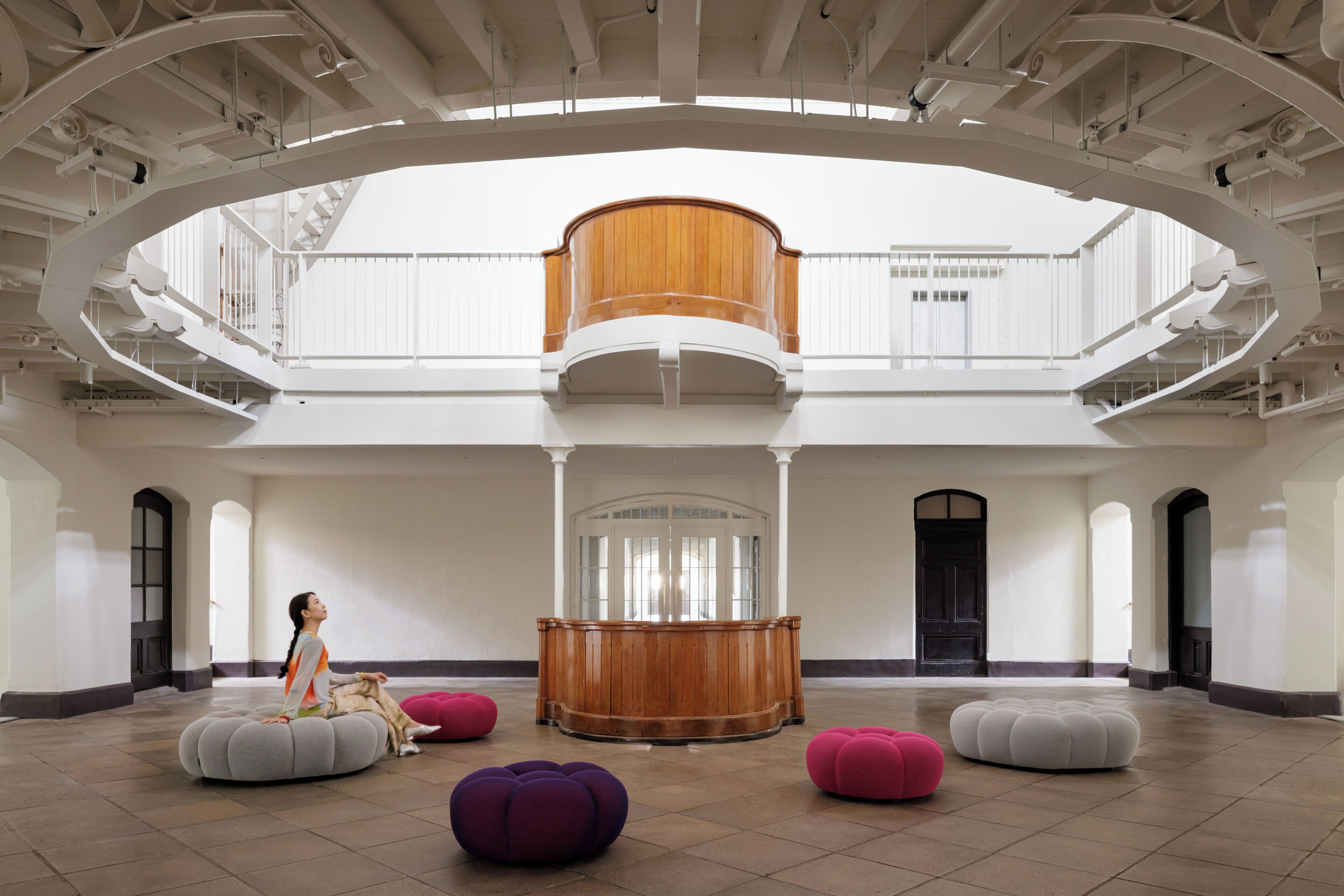 A spacious atrium with a central wooden column, multiple seating areas, and a balcony overlooking the space.
