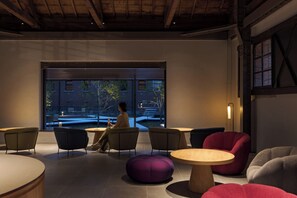Ein moderner Loungebereich mit Sitzgelegenheiten, einem groĂen Fenster und Blick ins Freie.