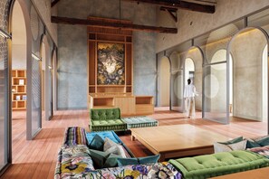 A spacious living area with a large sofa, a coffee table, and a green armchair. There is a wooden cabinet and a large artwork on the wall. - HOSHINOYA Nara Prison (Nara)