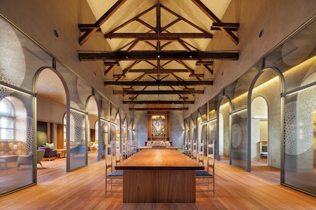 A spacious conference room with a long wooden table, high ceilings with exposed beams, and glass partitions with hexagonal patterns.. HOSHINOYA Nara Prison