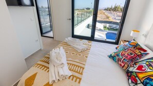A hotel room with a bed, a TV, a large window with a view, and a towel on the bed. - Dreamscape Villa by Fidalsa (Los Alcazares)
