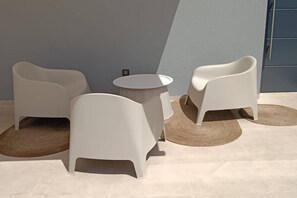 Ein modernes Zimmer mit einem runden Tisch, zwei Stühlen, einem kleinen Teppich und einem hellen Boden.