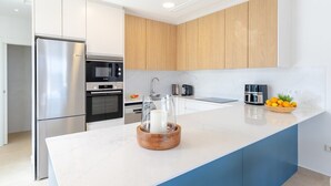 A modern kitchen with a large island, stainless steel appliances, and wooden cabinetry. - Dreamscape Villa by Fidalsa (Los Alcazares)