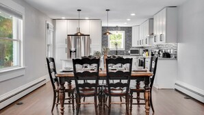 A modern kitchen with white cabinetry, stainless steel appliances, and a dining area with wooden chairs and a table. - Spacious Modern | Groups |Family |Sloans lake (Denver)
