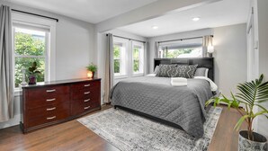 A bedroom with a large bed, a dresser, and a window with curtains. - Spacious Modern | Groups |Family |Sloans lake (Denver)