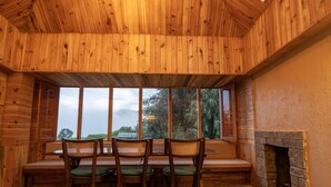 A wooden interior with a skylight, a fireplace, and a seating area with chairs and a table. - Zostel Homes Rajgundha (Multhan)