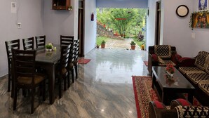 Una habitación con una mesa de comedor, sillas, un sofá, un ventilador de techo y vistas a un jardín.