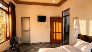 Un dormitorio con cama, escritorio, silla, televisor y ventilador de techo.