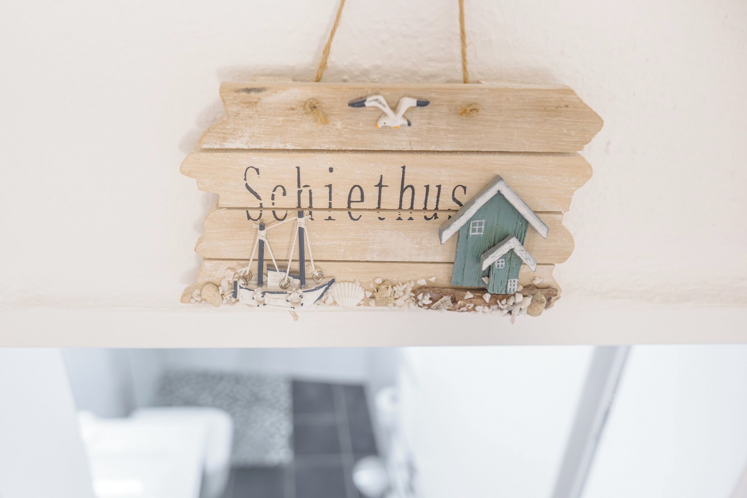 A wooden sign with the word "Schiethus" and a small house model.