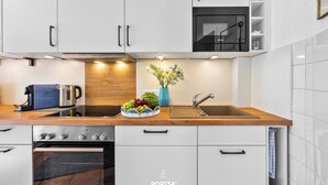 A modern kitchen with white cabinets, a built-in oven, a toaster, and a sink.