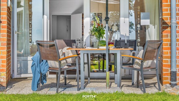 An outdoor dining area with a table, chairs, and a glass door leading to a patio.