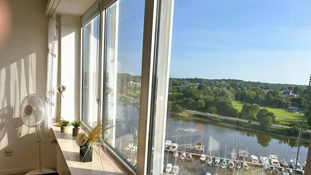 A room with large windows overlooking a marina with boats.