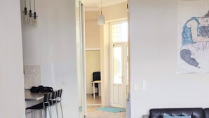 A spacious living area with a dining area, a black leather sofa, and a wooden coffee table.