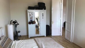 A bedroom with a bed, a wardrobe, a suitcase, and a bicycle.