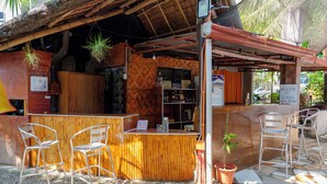 A rustic bar area with a wooden counter, metal chairs, and a small potted plant. - Silang Beach Resort and Diving (Dauin)