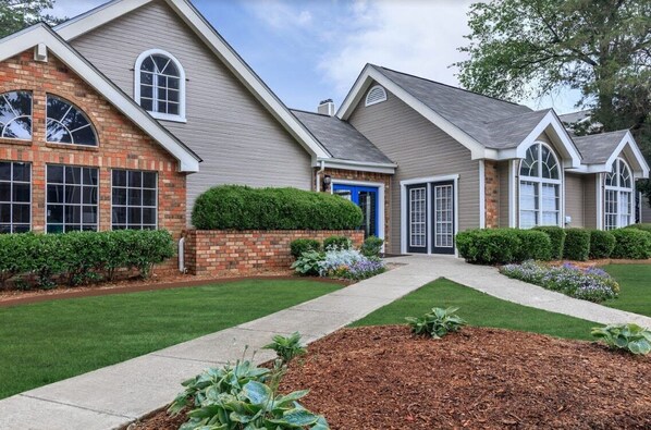 A two-story house with a brick facade, a blue front door, and a well-maintained lawn.
