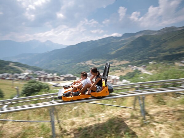 Des montagnes russes avec des passagers, le tout se détachant sur un paysage montagneux.