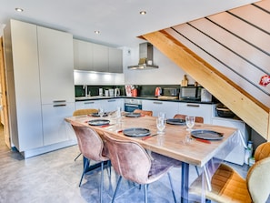A modern kitchen with a dining area, featuring a wooden table, chairs, and built-in appliances.