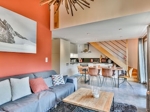 A modern living room with a sofa, coffee table, and dining area with chairs.