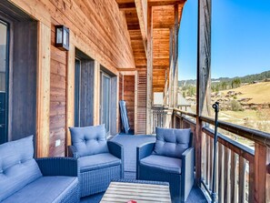 A wooden balcony with wicker furniture and a view of a rural landscape.