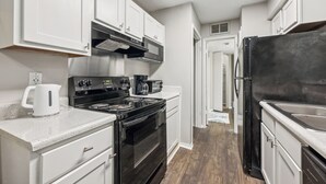 A compact kitchen with white cabinetry, a black stove, and a black refrigerator.
