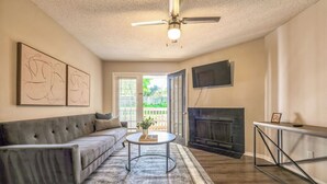 A living room with a grey sofa, a round coffee table, a fireplace, and a ceiling fan.