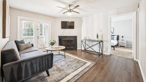 A living room with a sofa, coffee table, fireplace, and ceiling fan.