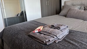 Una cama bien hecha con una toalla doblada y un objeto rojo y blanco estampado sobre ella.