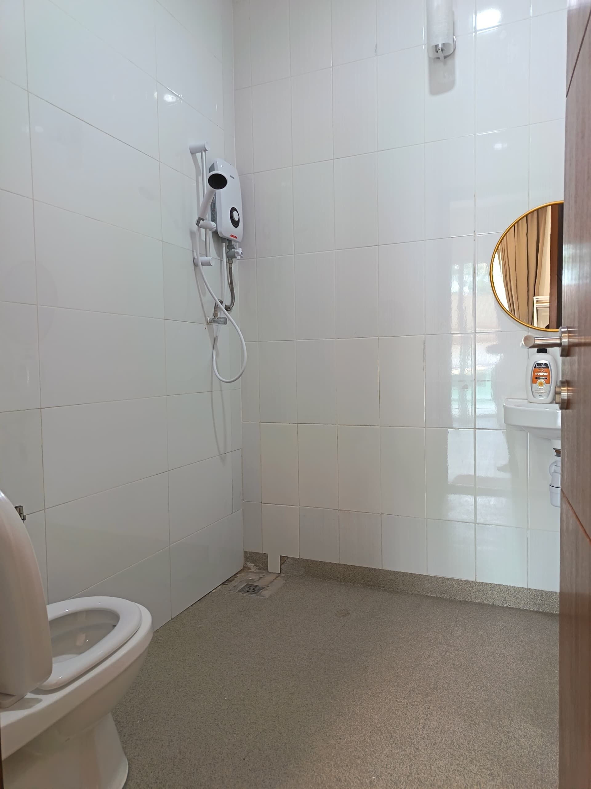 A small, clean bathroom with white tiles, a toilet, a sink, and a shower.
