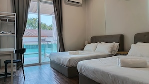 Une chambre d’hôtel avec deux lits, un bureau et une vue sur une piscine.
