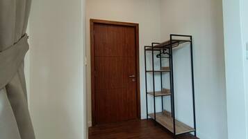 A hallway with a wooden door and a metal shelving unit against the wall.