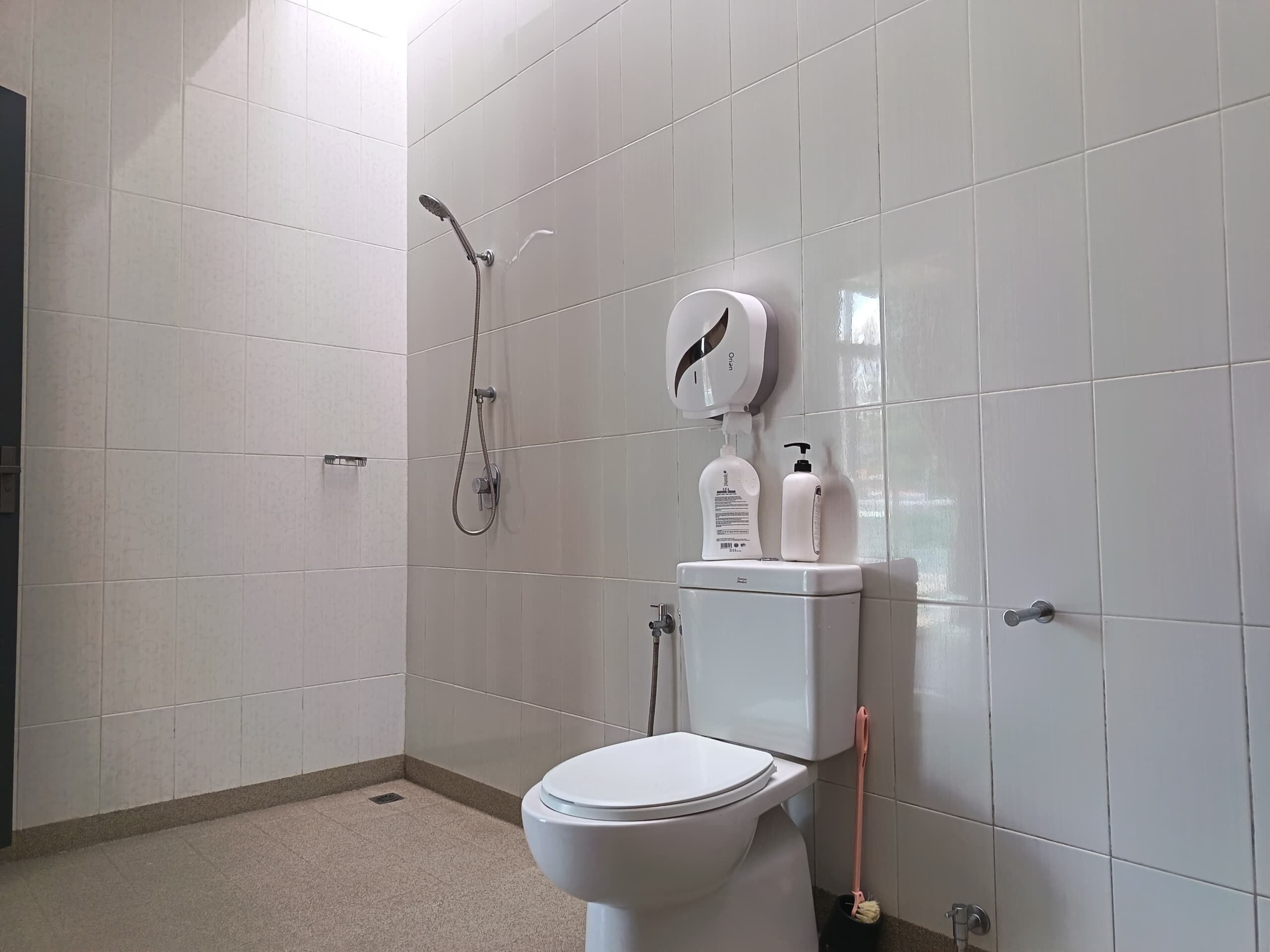A modern bathroom with a toilet, a shower, and a hand dryer.