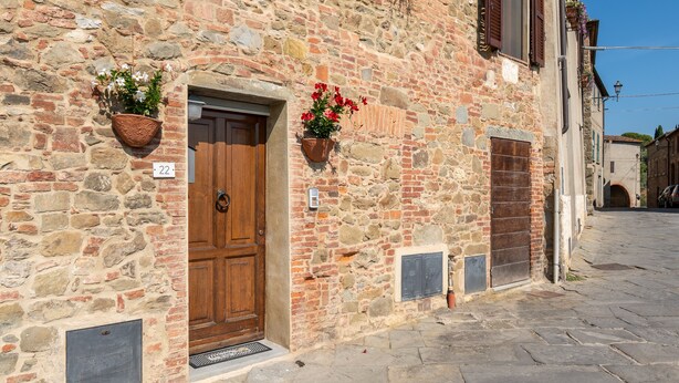 A stone building with a wooden door, two flower baskets, and a number '22' sign. - Apartment 'Piccolo Rustico' with Mountain View, Wi-Fi and Air Conditioning (Scrofiano)