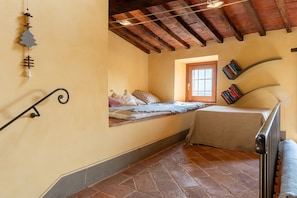 A bedroom with a sloped ceiling, a window, a bed, a radiator, and a bookshelf. - Apartment 'Piccolo Rustico' with Mountain View, Wi-Fi and Air Conditioning (Scrofiano)