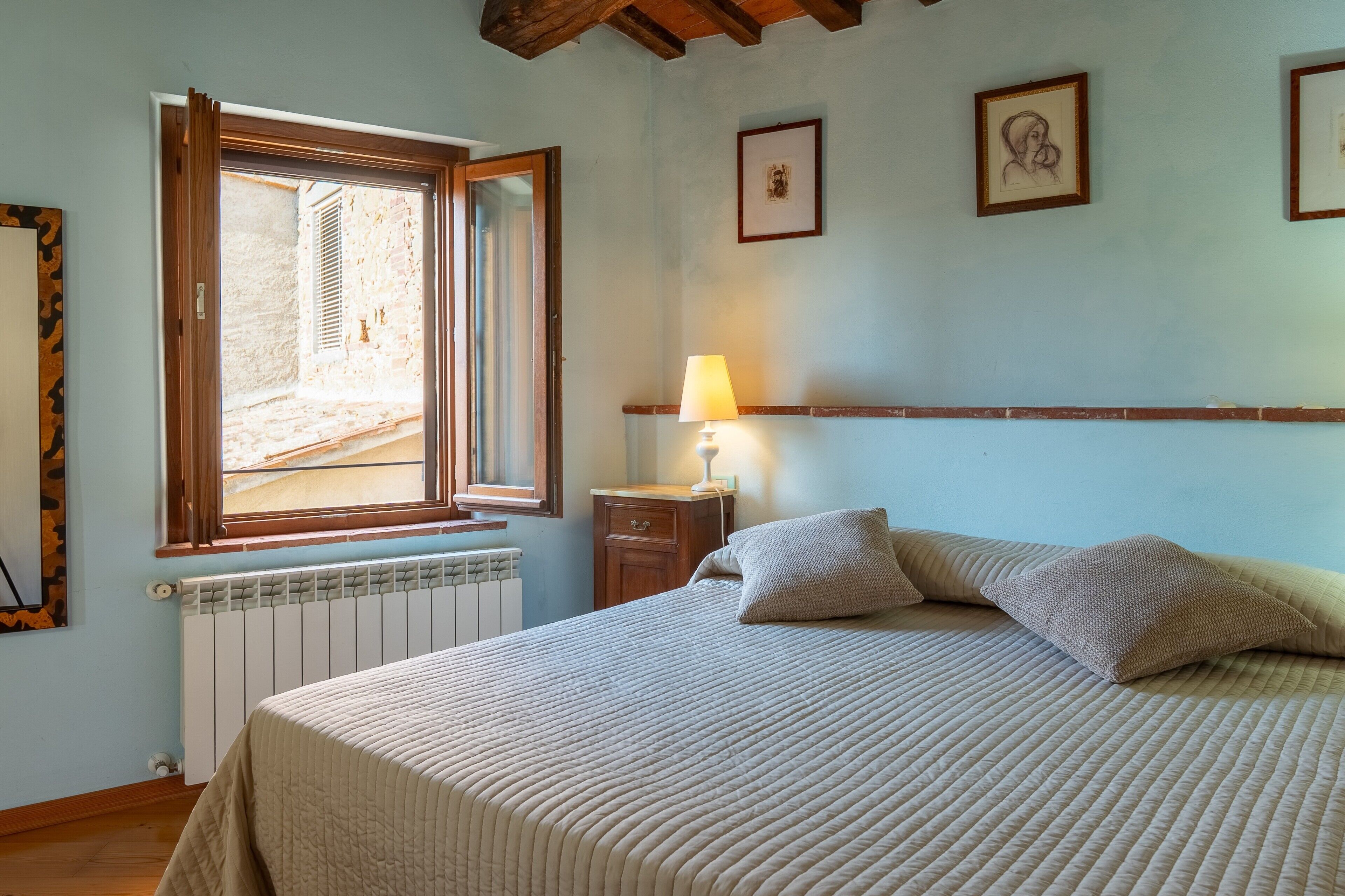 Une chambre à coucher avec un lit, une fenêtre, un radiateur et une lampe.
