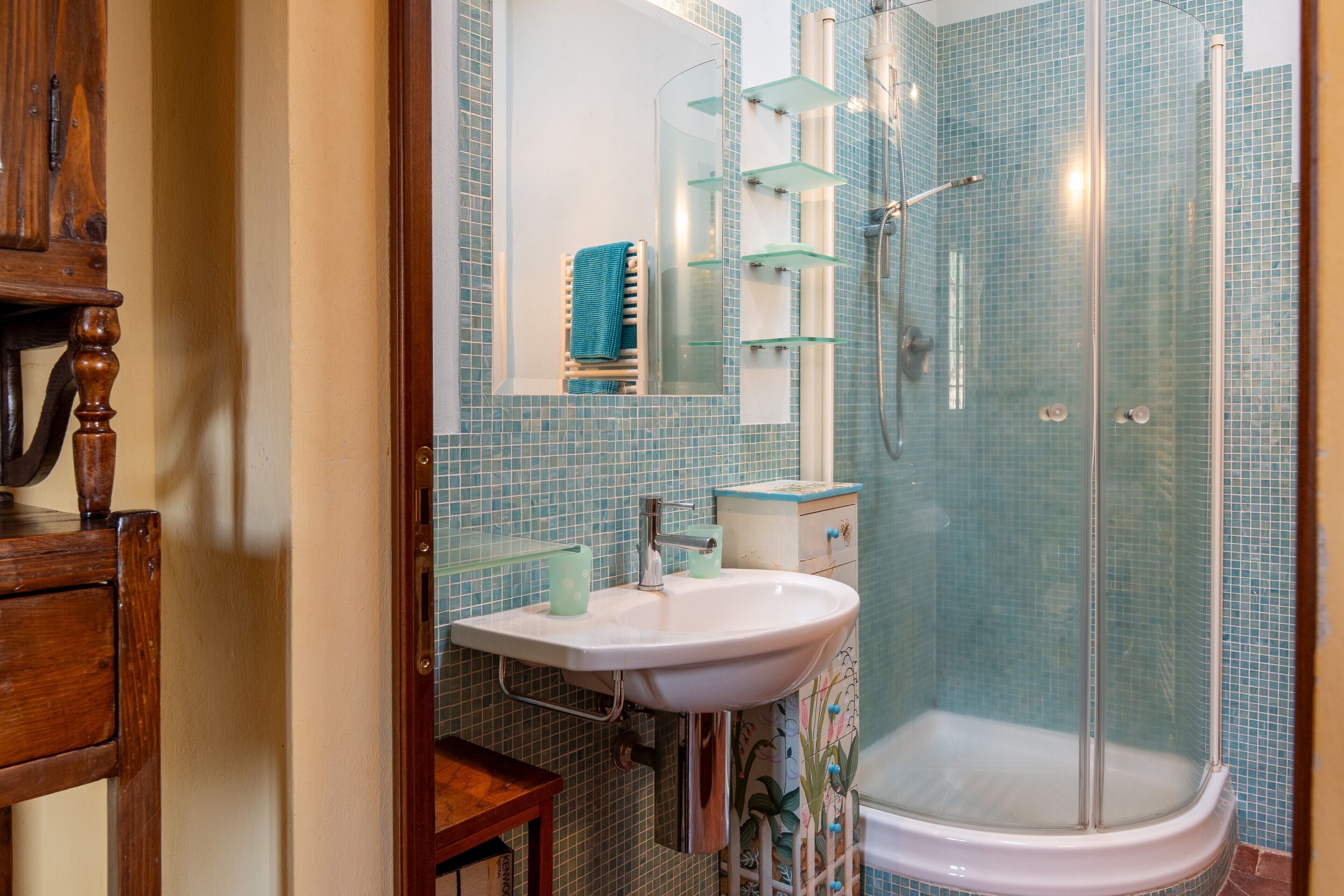 Un baño con cabina de ducha de vidrio, lavabo con espejo y mueble de madera.