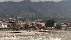 A river with a bridge and buildings in the background. - Hotel Himalaya (Bhuntar)