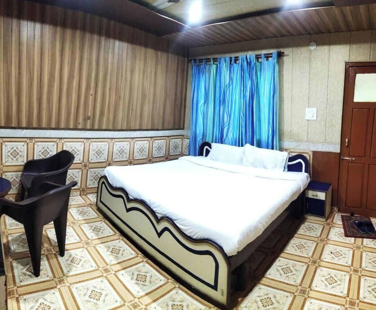 A bedroom with a bed, a nightstand, a chair, and a window with curtains.
