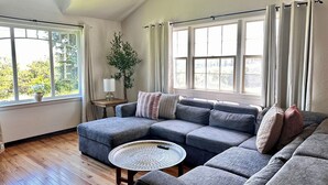Een moderne woonkamer met een hoekbank, een ronde salontafel en een potplant.