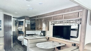 Un intérieur de camping-car compact comprenant un coin cuisine, un espace salon et une grande fenêtre.