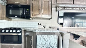 Une cuisine compacte équipée d’une cuisinière, d’un four, d’un four à micro-ondes et d’un petit évier.